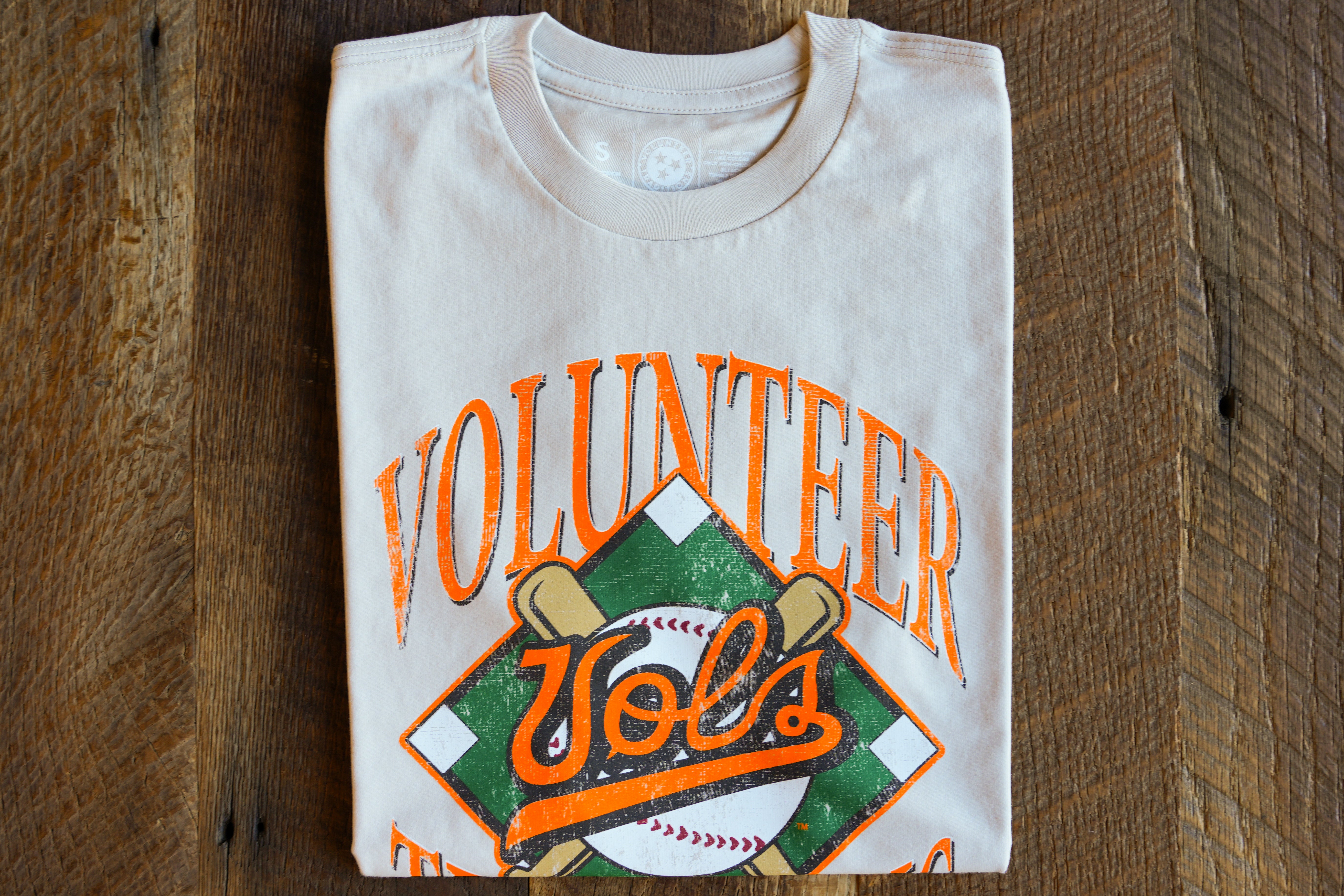 Folded cream t-shirt with 'Diamond Vols' design on a wooden surface
