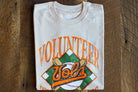 Folded cream t-shirt with 'Diamond Vols' design on a wooden surface