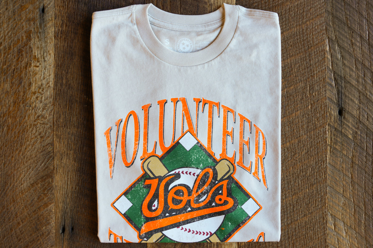 Folded cream t-shirt with 'Diamond Vols' design on a wooden surface
