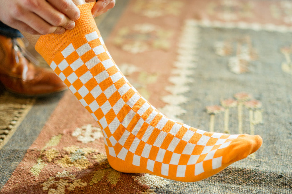 Volunteer Traditions University of Tennessee Licensed Socks. Orange and White Checkerboard sock bundle on foot.
